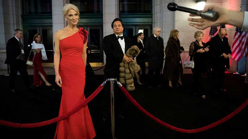 Kellyanne Conway answering to press while her husband George Conway stands behind her.